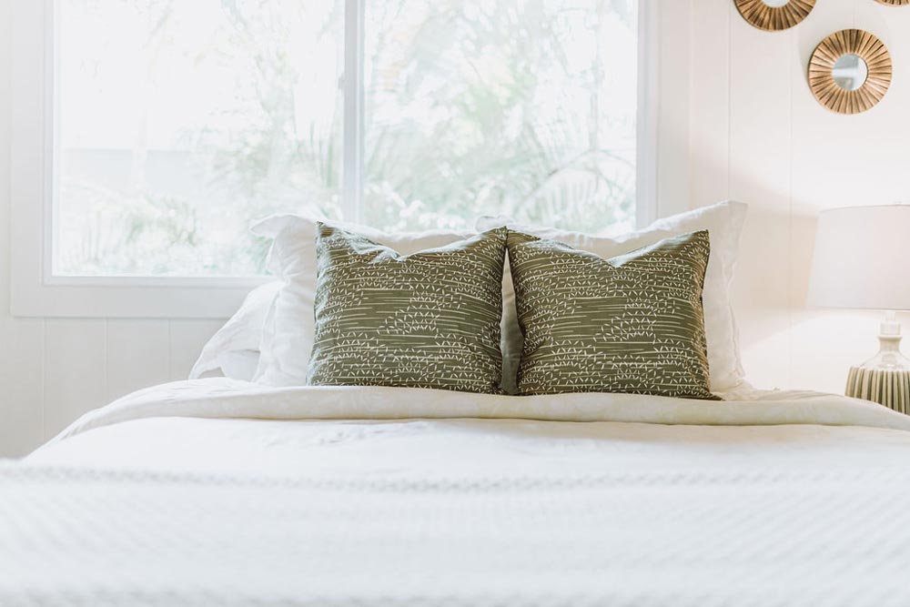NOHO HOME Contract Residential Project Image Of Two Colorful Olive Hawaiian Pillows On a White King Bed