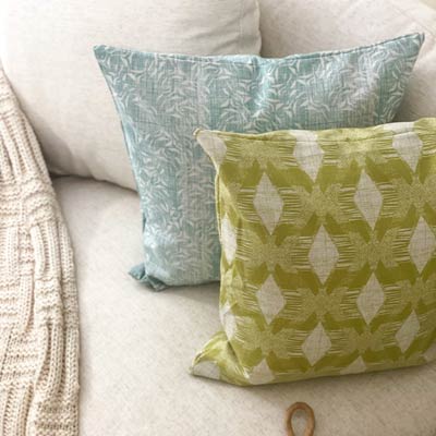 Light Green and Light Blue NOHO HOME Licensed Pillows On a White Couch